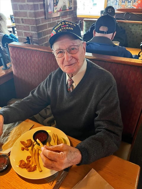Male World War 2 Veteran sitting at an Applebee's table eating an entree with french fries.